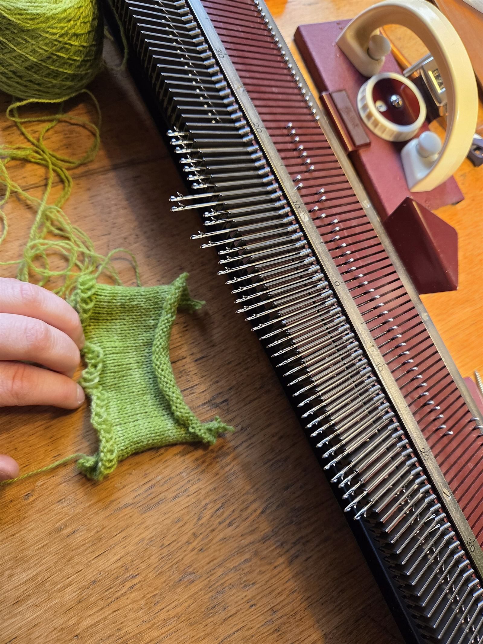 A hand knitting machine with green yarn